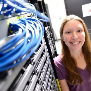 A female student smiles next to a server.