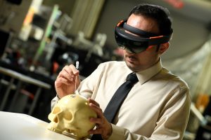 Professor Ehsan Azimi wears augmented reality glasses and probes a phantom skull.