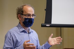 Misha Kazhdan wearing a mask and gesturing, as if giving a presentation.