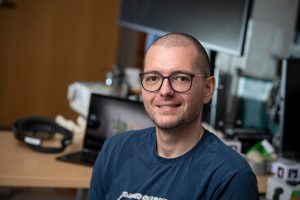 Headshot of Mathias Unberath in front of a desk with a laptop and VR equipment.