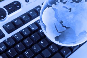 A blue glass globe of Earth sits on a black keyboard.