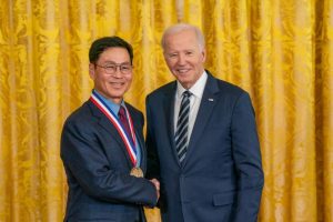 Wearing a medal, Jeong Kim poses with President Biden.