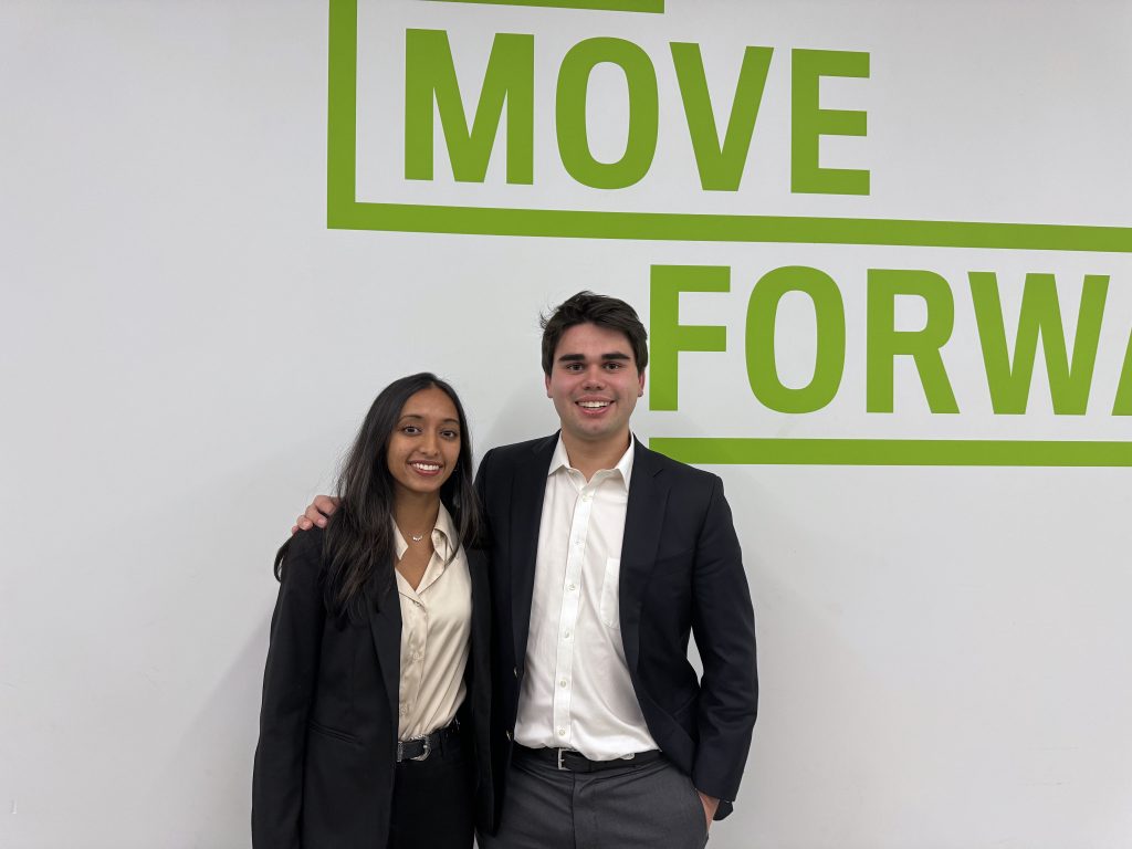 Iris Gupta and Charlie Wheelock pose in front of a white wall with green text reading "MOVE FORWARD".