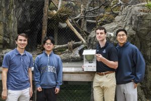 Students from the Johns Hopkins Multidisciplinary Engineering Design course showcase their bobcat feeding system in front of the bobcat enclosure at the Maryland Zoo.