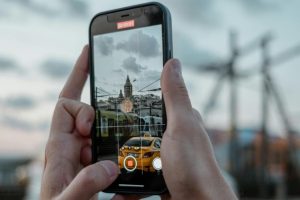 Someone holding a smartphone records footage of a city scene.