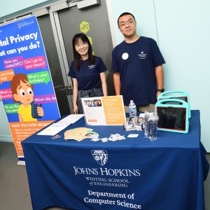 Lanjing Liu and Yaxing Yao pose behind a table reading Johns Hopkins Whiting School of Engineering Department of Computer Science and in front of a banner reading Digital Privacy What can you do?