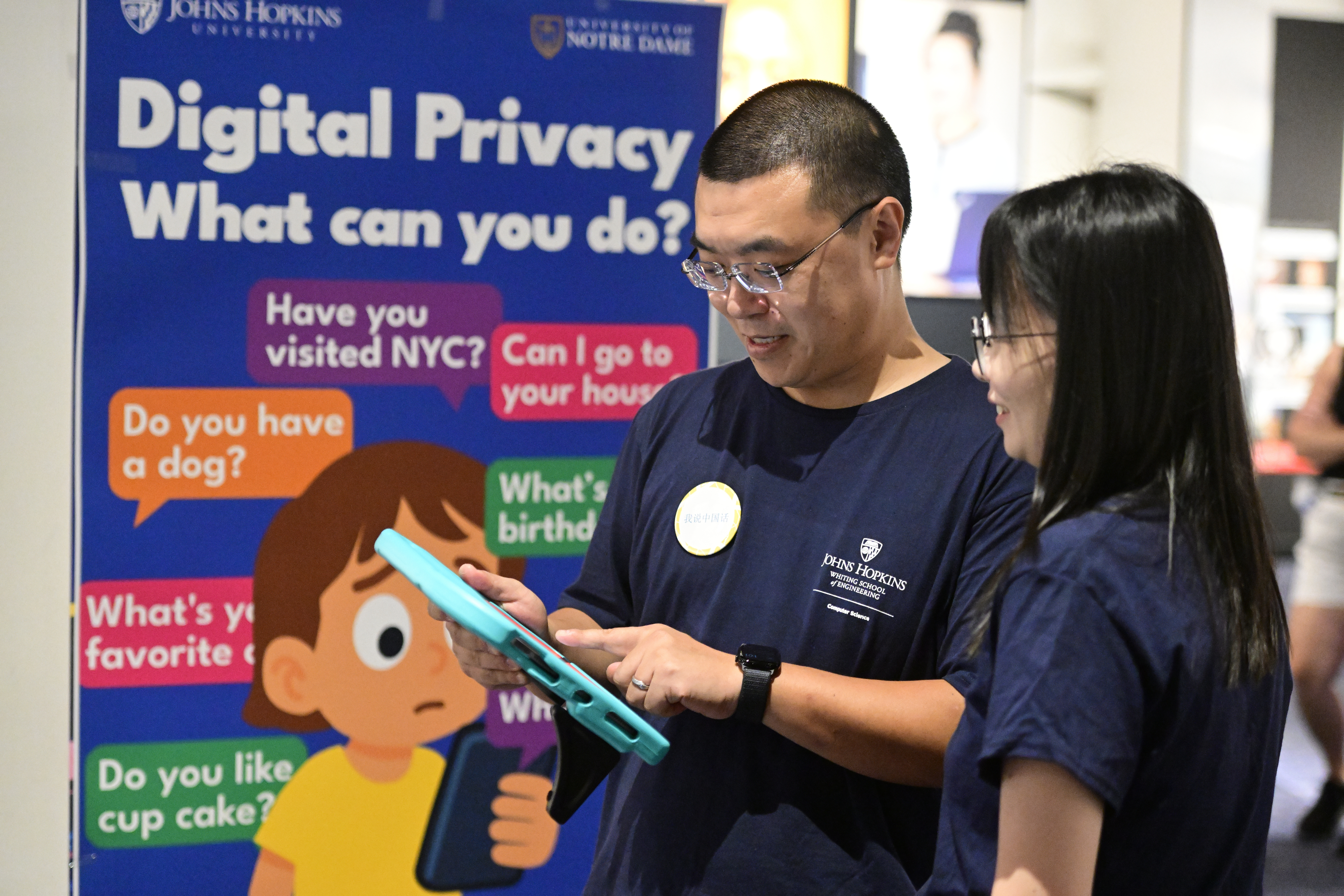 Yaxing Yao and Lanjing Liu look at a tablet in front of the digital privacy banner.