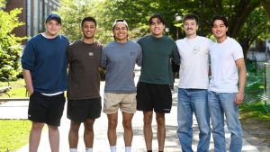 Griffin Montalvo, Taran Agarwal, Justin Bravo, Bryan Santana, Simon Rupp, and Dhilan Patel smile for the camera with their arms around each other.