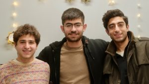 Barak Reibman, Tarik Metin, and Ibrahim Jehanzeb pose in front of star lights.