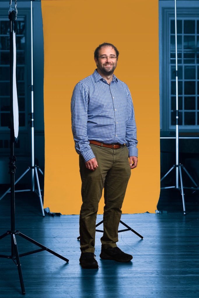 Alex Marder standing in front of a yellow backdrop.