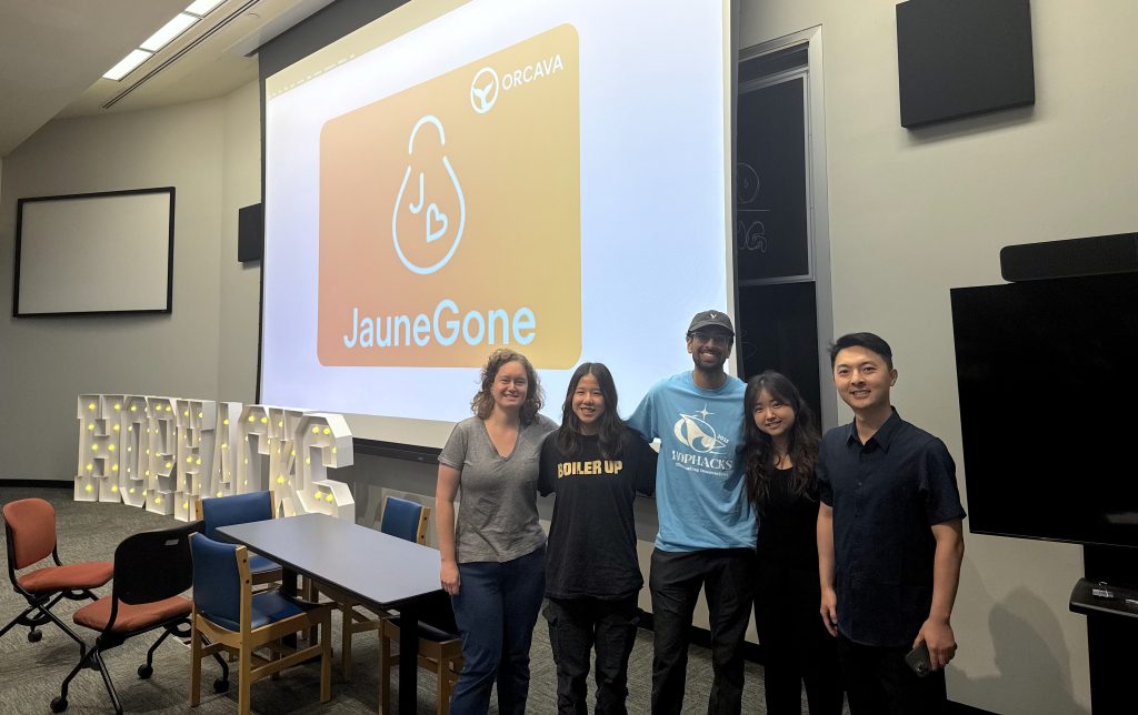 The JauneGone team poses in front of a projector with their logo on it.