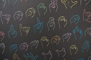 Colorful sign language handshapes on a black background.