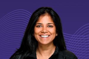 Headshot of Suchi Saria on a blue grid background.