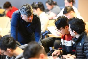 Gagan Garg explains to two students sitting in his Intro Algorithms class.