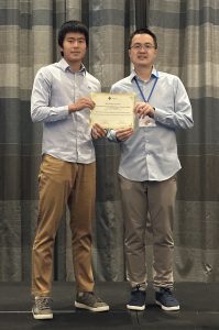 Steven Tan and a conference organizer pose with a certificate.