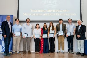Randal Burns, Brandon Stride, Eric Nalisnick, Jan Emily Mangulabnan, Subhasri Vijay, Maria Romo Nichols, Ziang Xiao, Michael Rushanan, and Joel Dean, Jr. pose in front of a projector screen displaying the words "Teaching, Advising, and Mentorship Awards Celebration." Everyone but Burns and Dean holds a framed award certificate.