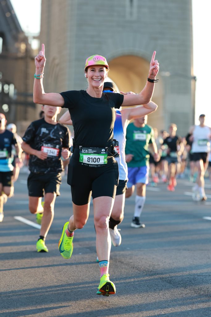 Alexis Dean running the Sydney Marathon posing with both hands up making "number one" signs.
