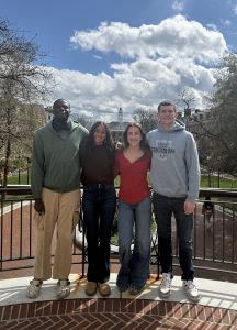 Lamine Niang, Sahana Sanjeev, Mirra Klimov, and Radomyr Couture pose in front of the Wyman Quad.
